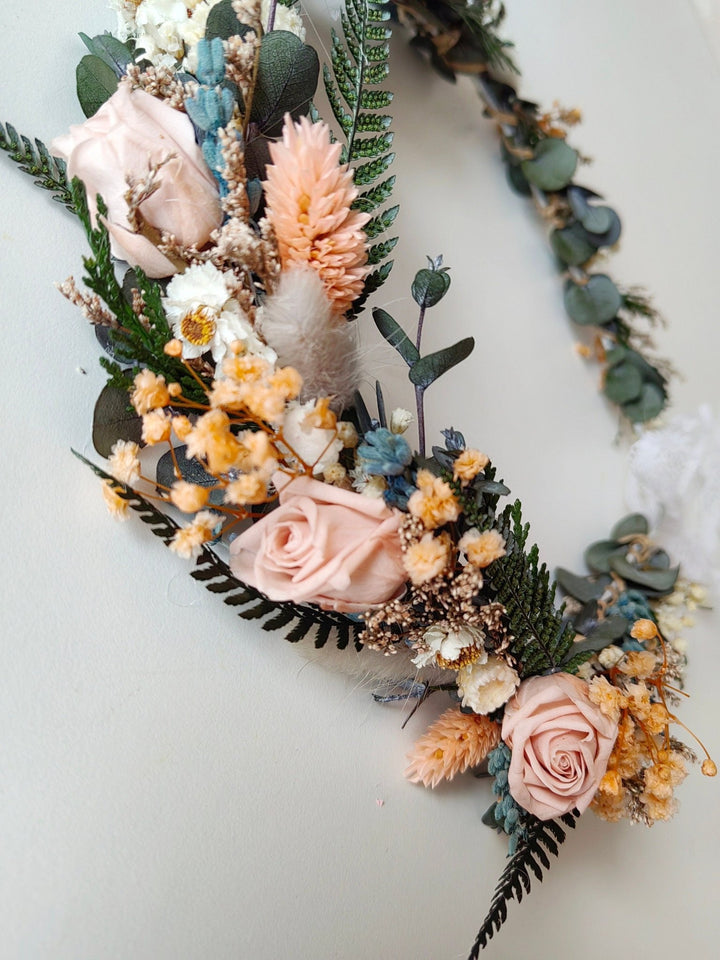Floral wreath with pink, orange, cream and green flowers on a white background