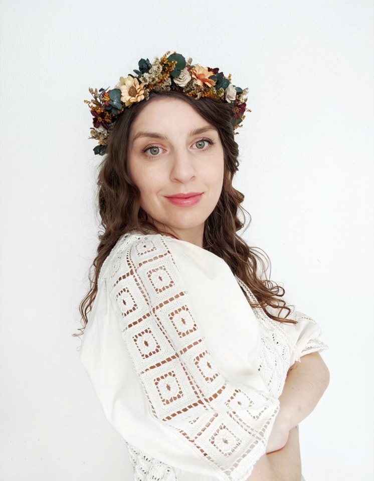 Woman wearing a floral headpiece and white lace shawl on a light background