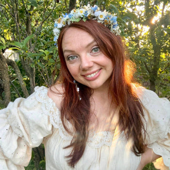 Woman wearing a floral crown and white dress in a garden setting