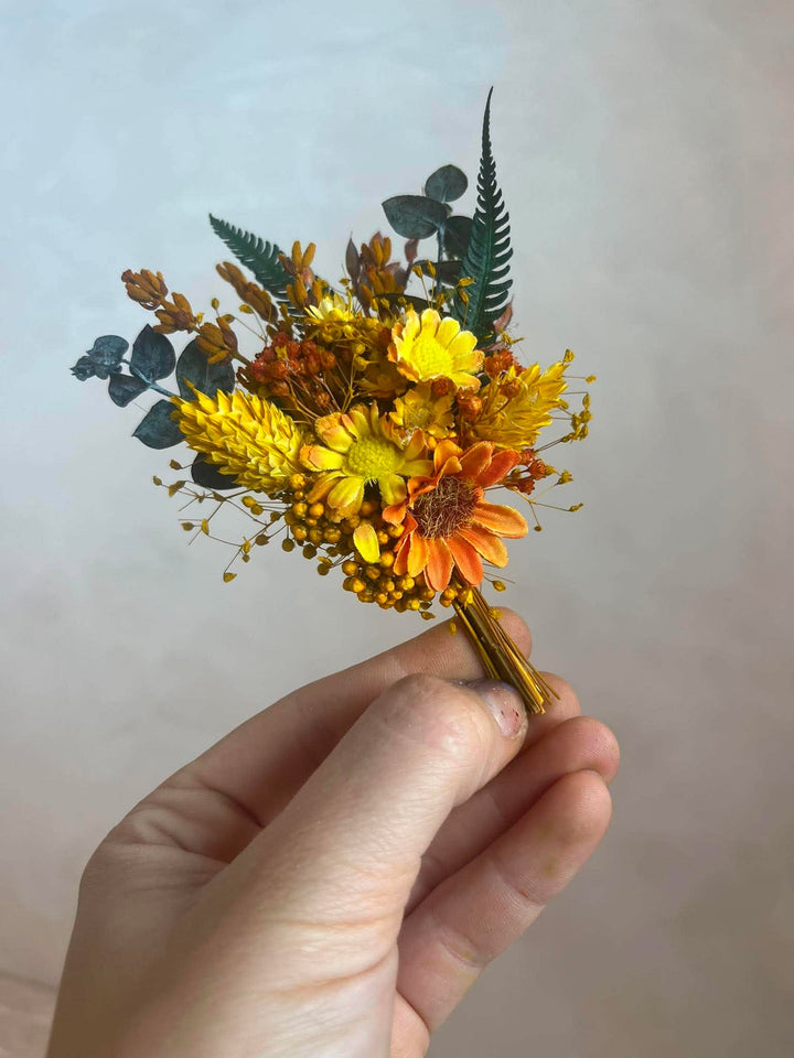 Orangenes und gelbes Knopflochbukett mit Sonnenblume, Gänseblümchen und Farn