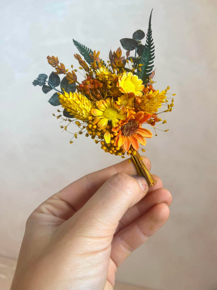 Orangenes und gelbes Knopflochbukett mit Sonnenblume, Gänseblümchen und Farn