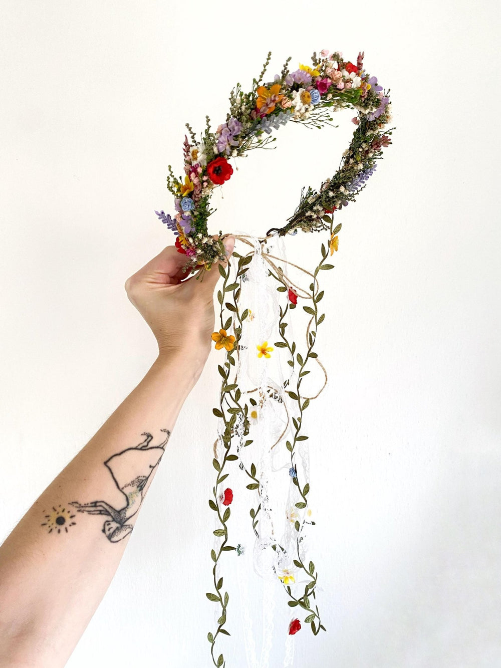 Hand holding bohemian flower crown with flowing veil, handcrafted bridal headpiece detail