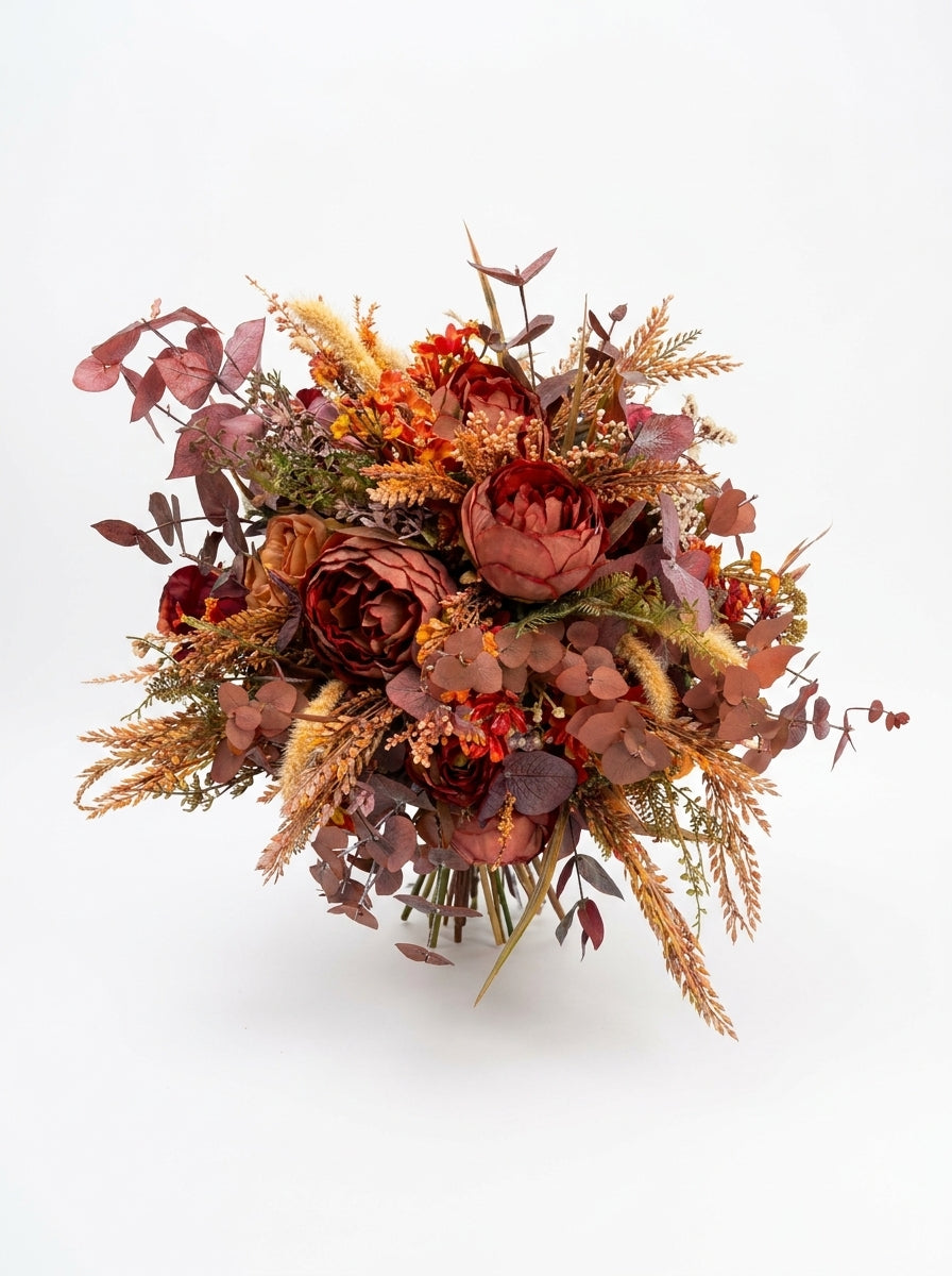An autumn-themed flower bouquet featuring burgundy peonies, rust-orange grasses, and dusty rose eucalyptus, presented on a clean white background.