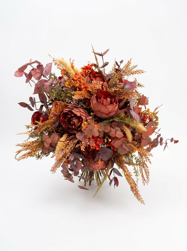 An autumn-themed flower bouquet featuring burgundy peonies, rust-orange grasses, and dusty rose eucalyptus, presented on a clean white background.