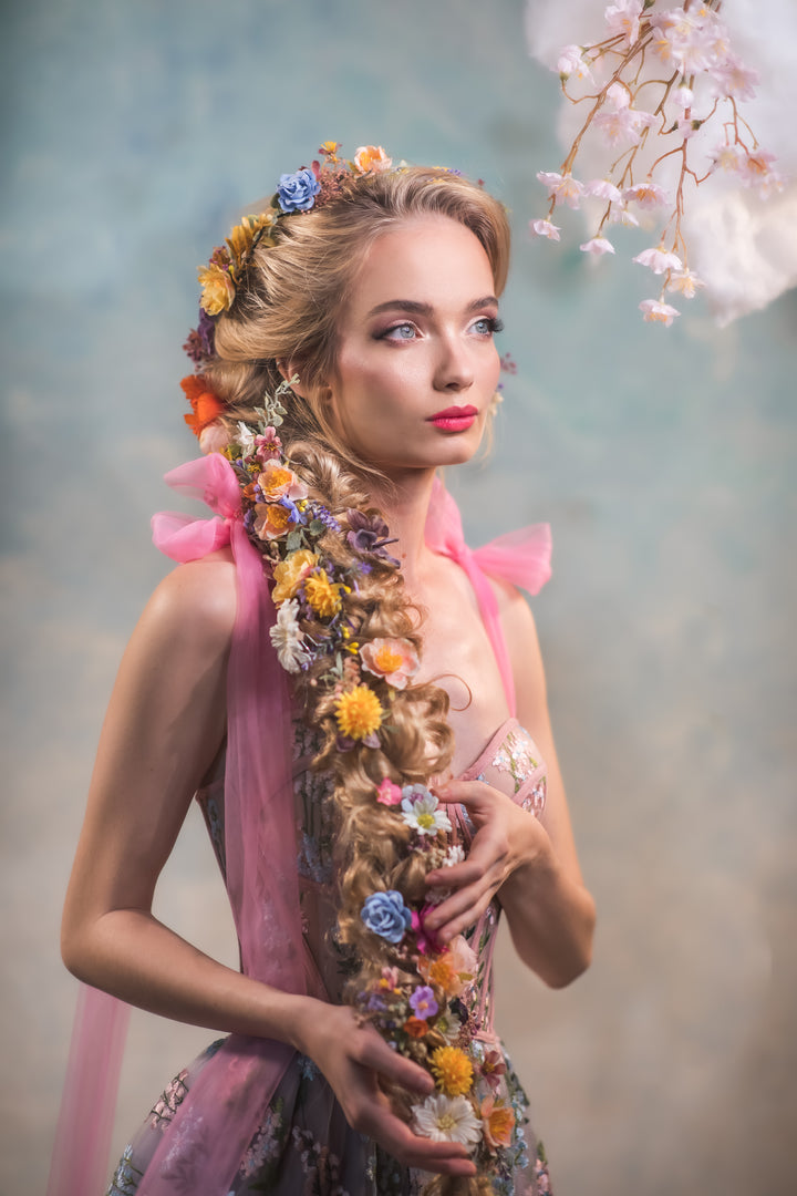 Woman with floral hairpiece and dress against a soft, blurred background