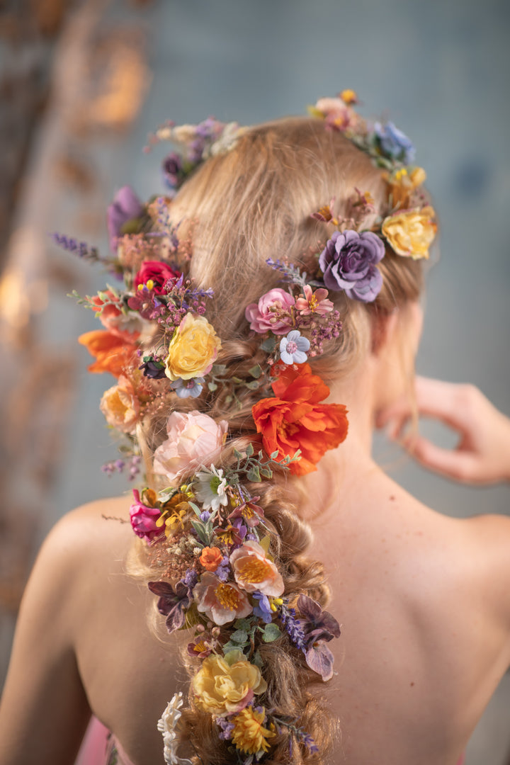 Woman with a floral hairpiece and braided hair against a blurred background