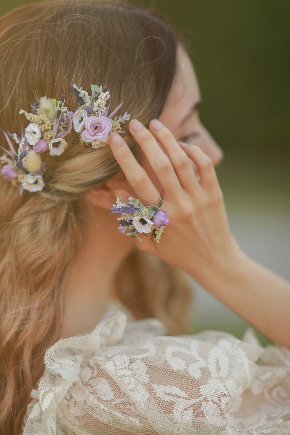 Woman wearing a floral hairpiece with matching floral ring  a blurred background
