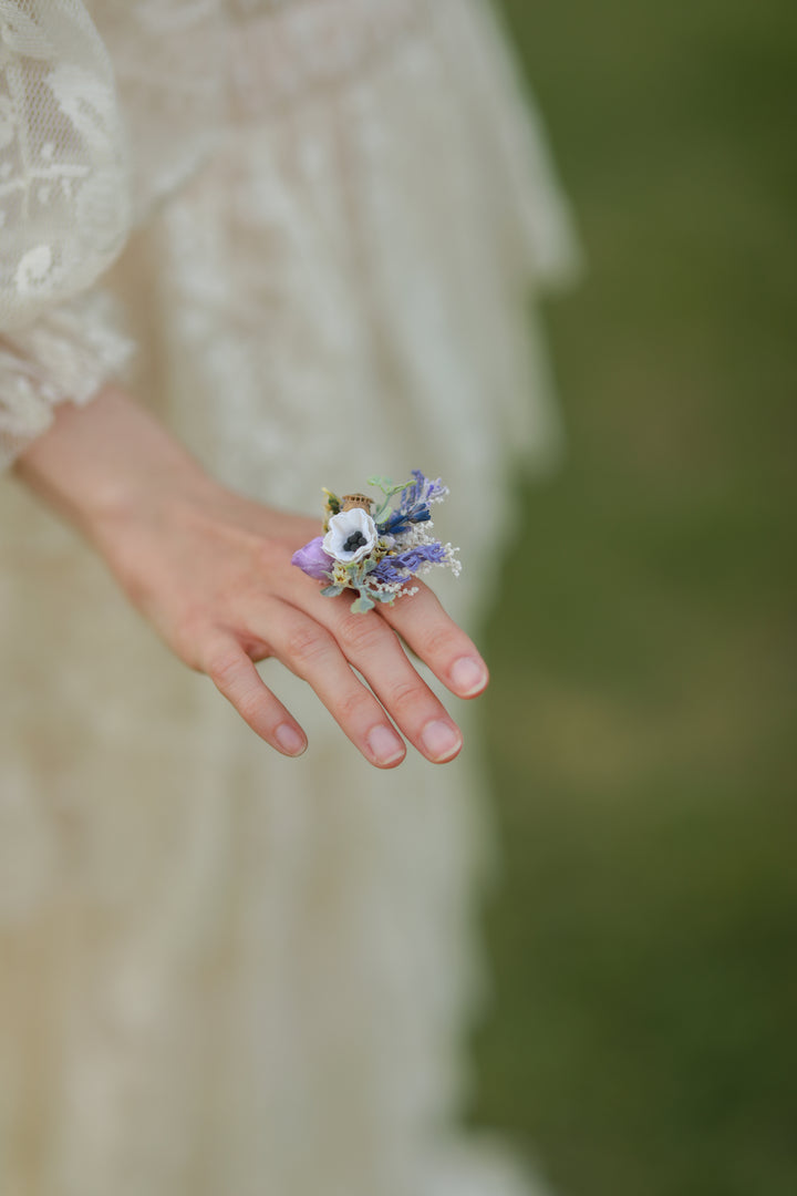 Hand holding a small floral arrangement on ring a blurred background