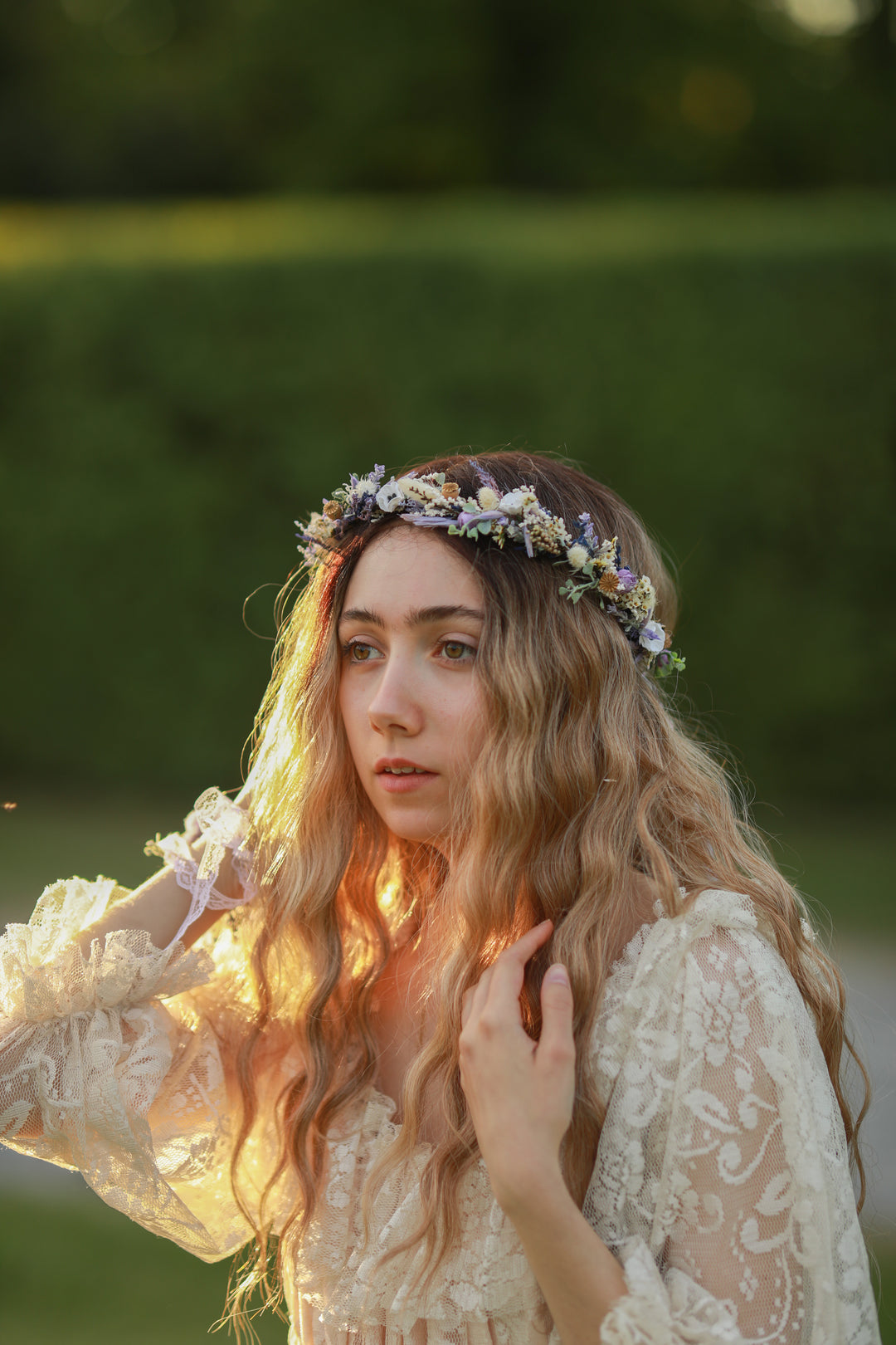 Woman with a floral purple and cream crown in a natural setting