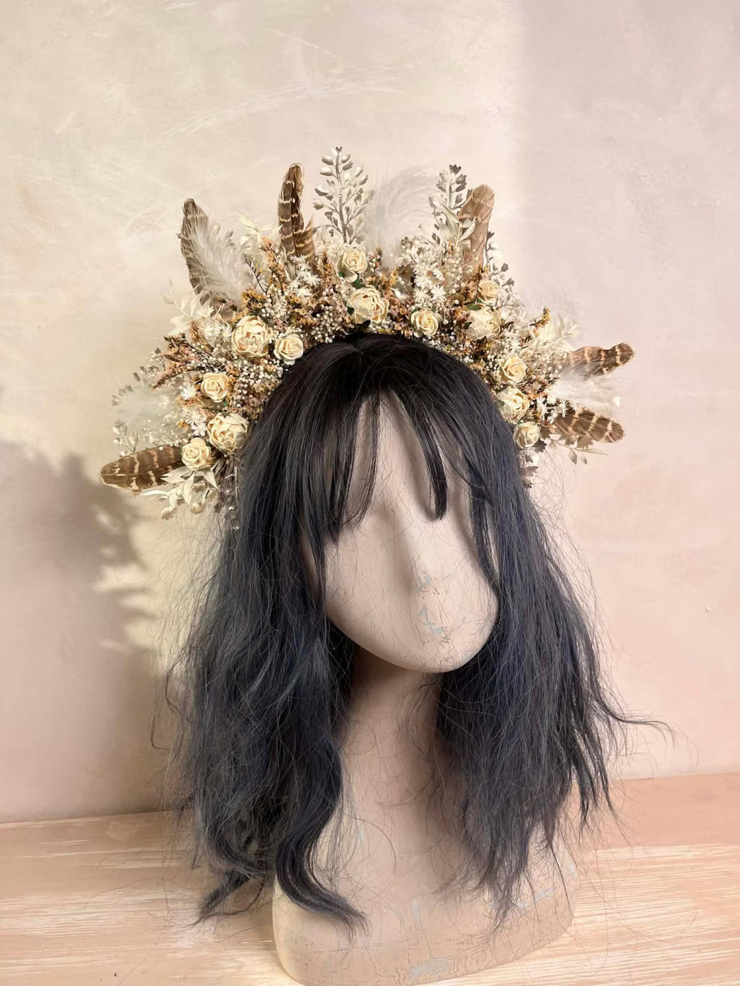 Mannequin head with dark hair wearing a decorative headpiece on a beige background