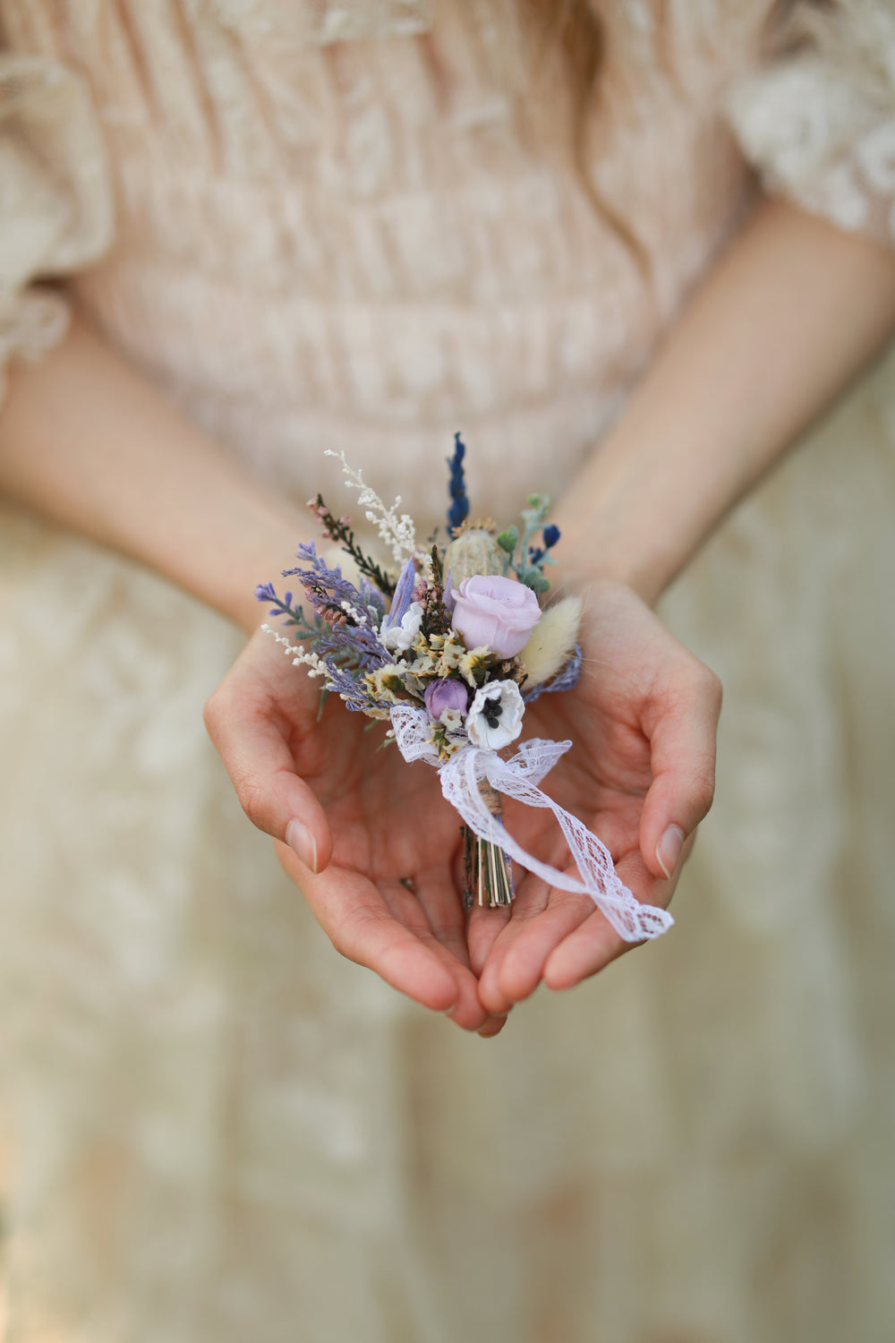 Person holding a classic boutonniere with a blurred background