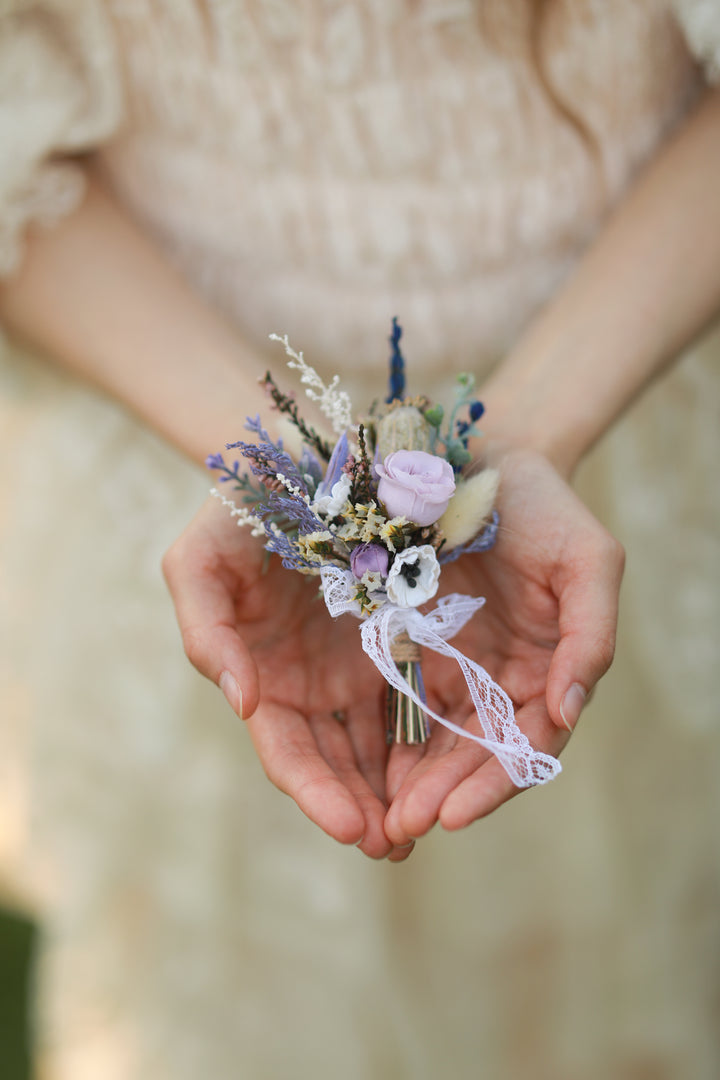 Person holding a small bouquet of flowers with a blurred background
