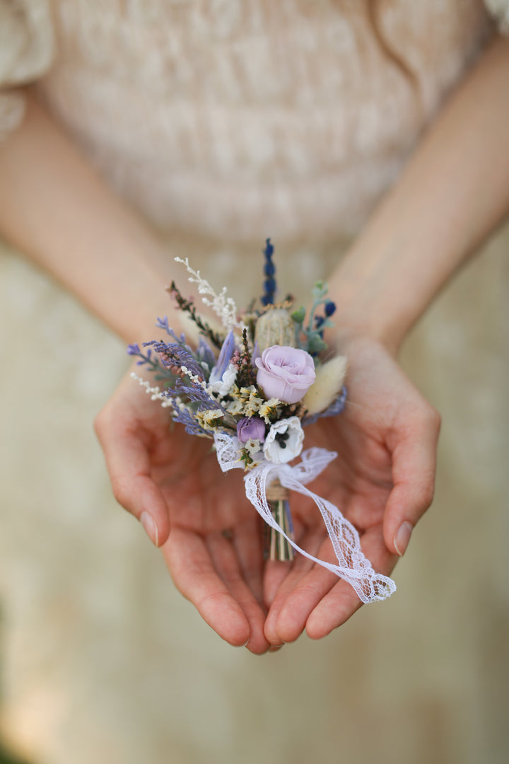 Person holding classic boutonniere for groom with a blurred background