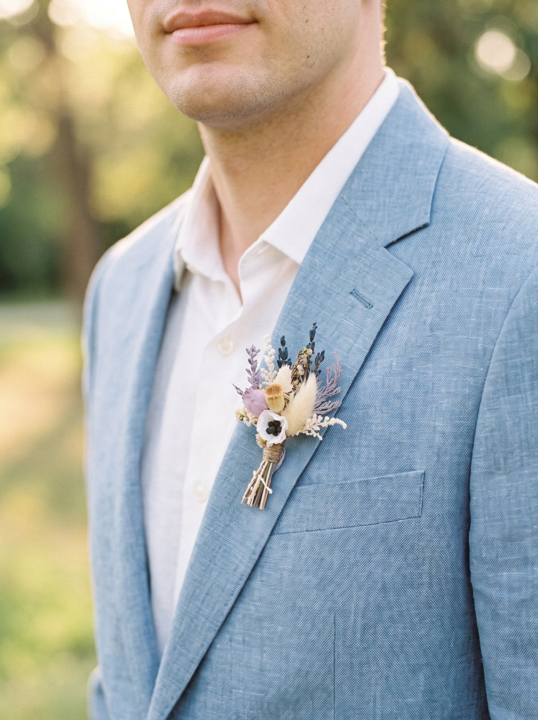 Man wearing a light blue suit with a floral boutonniere outdoors