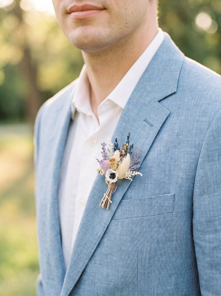 Man wearing a light blue suit with a floral boutonniere outdoors