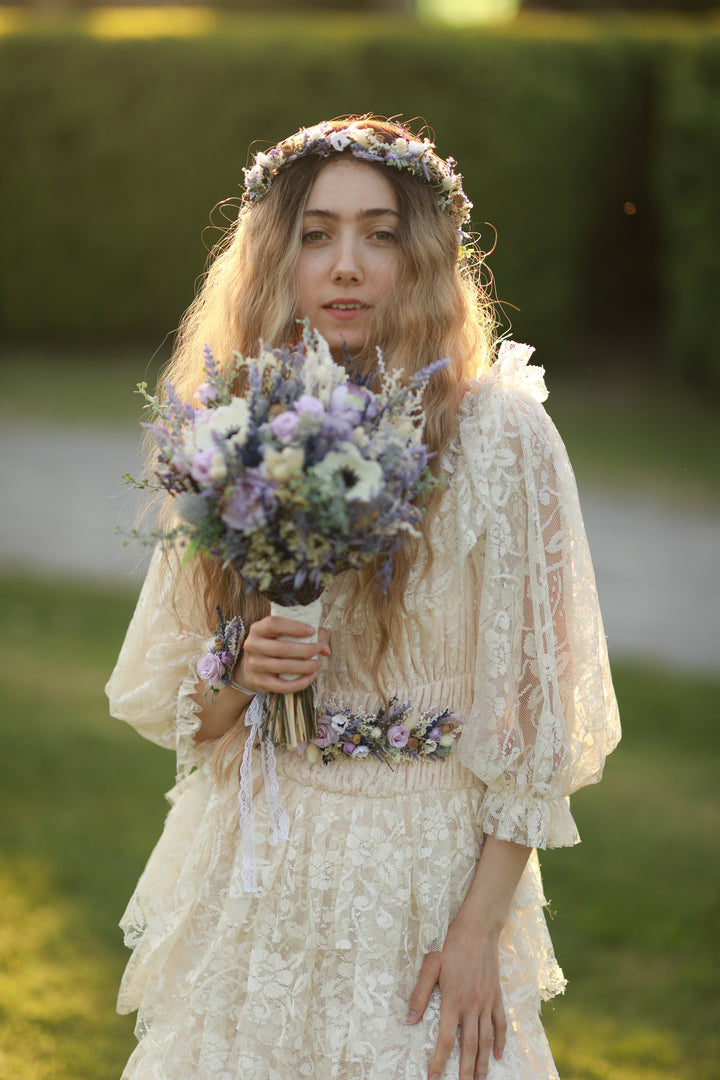 Woman in a lace dress holding a bouquet of flowers outdoors