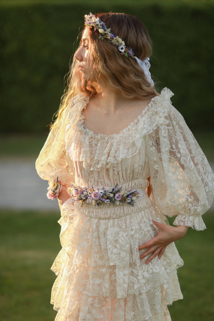 Woman in a vintage-style dress with floral accessories standing outdoors.