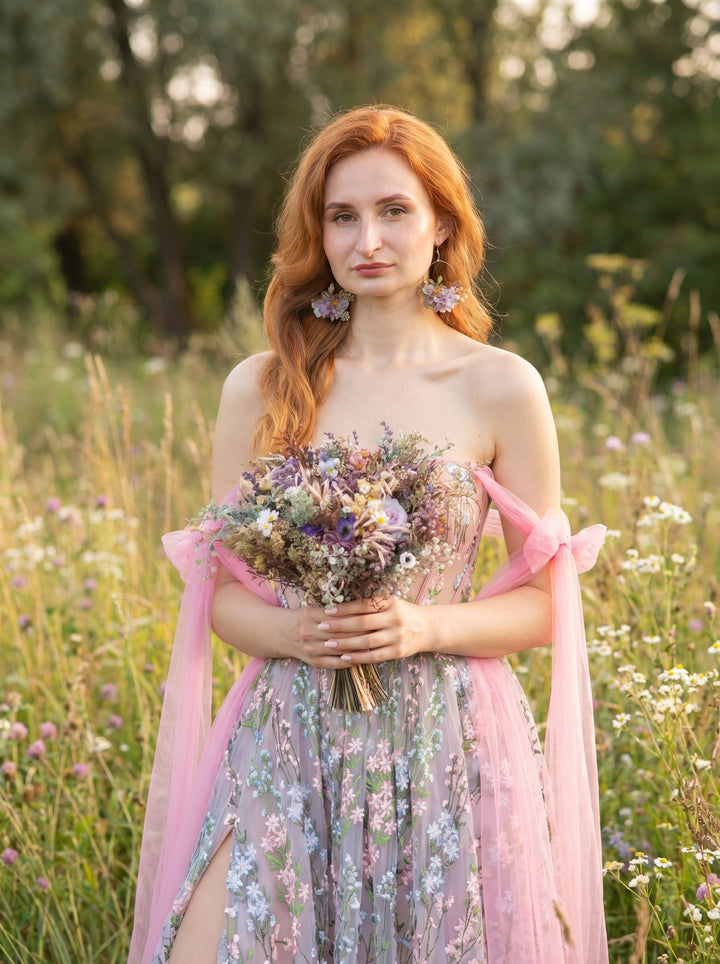 Woman in a floral dress holding a bouquet of flowers in a field