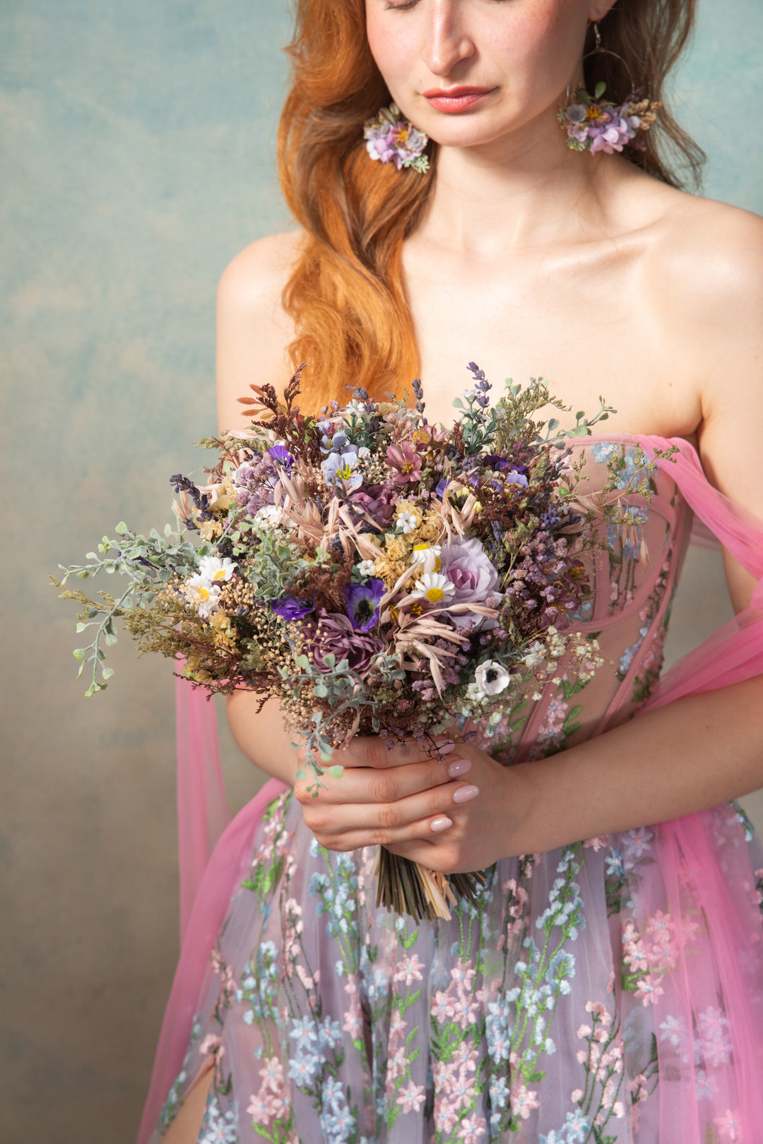 Woman holding a bouquet of flowers wearing a floral dress against a soft background