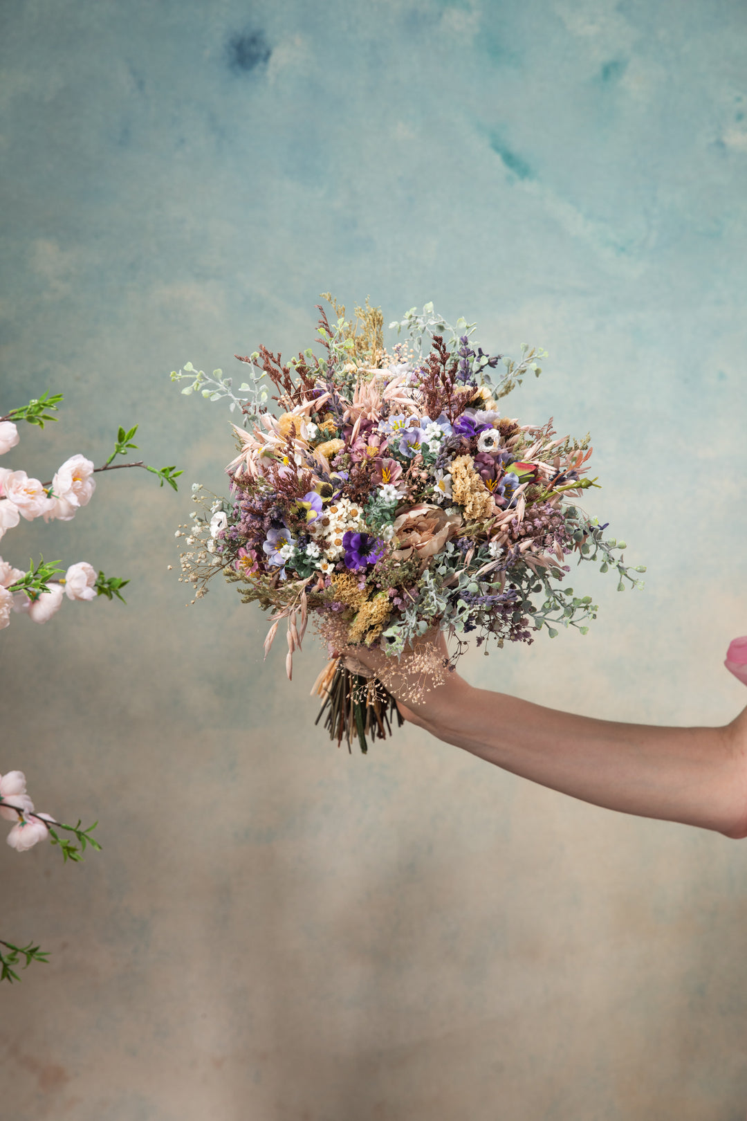 Hand holding a bouquet of flowers against a textured background