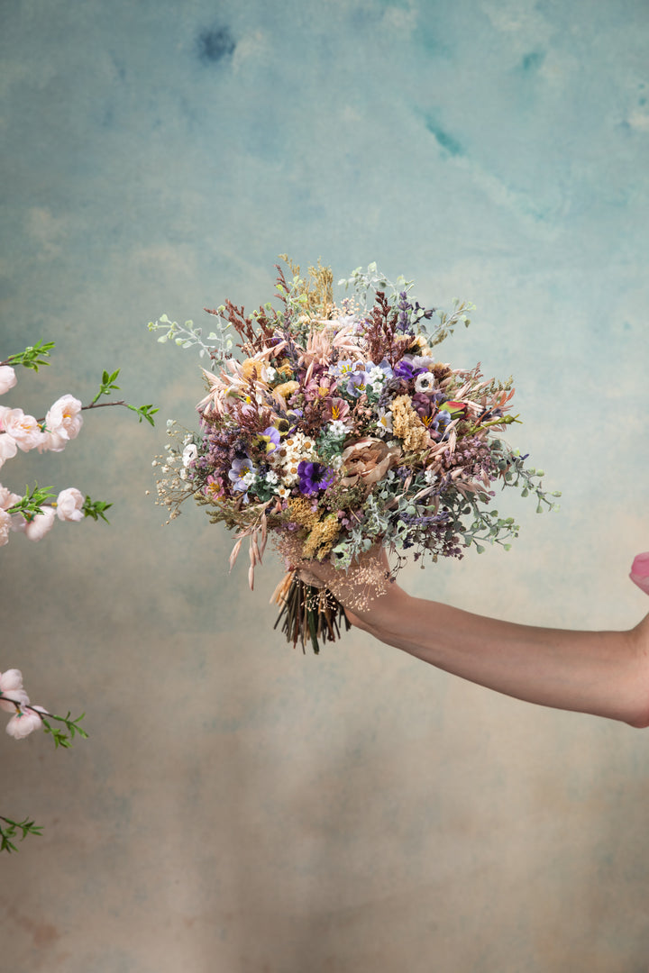 Hand holding a bouquet of flowers against a textured background