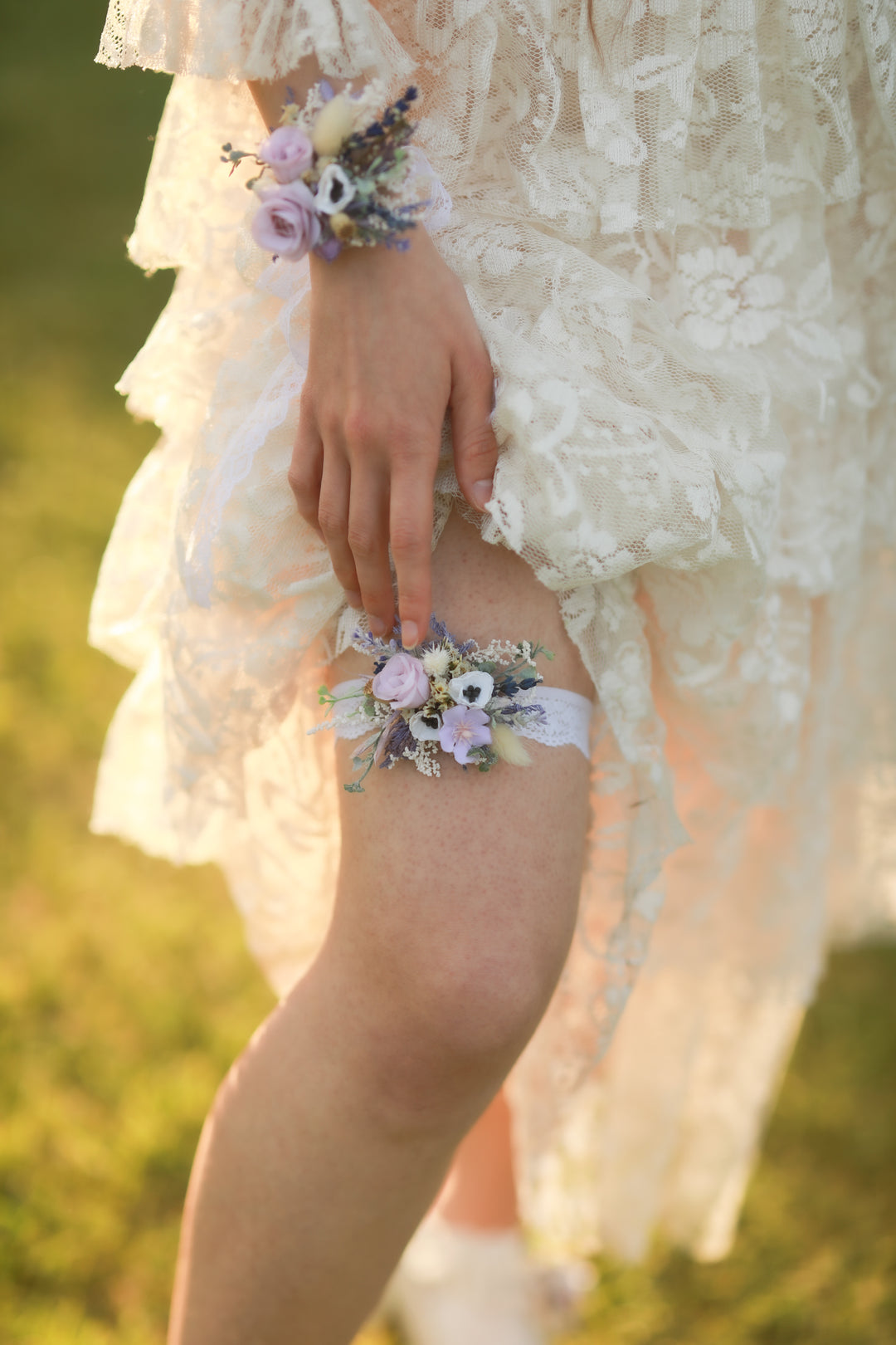 Person wearing a floral corsage on their wrist and leg against a blurred natural background