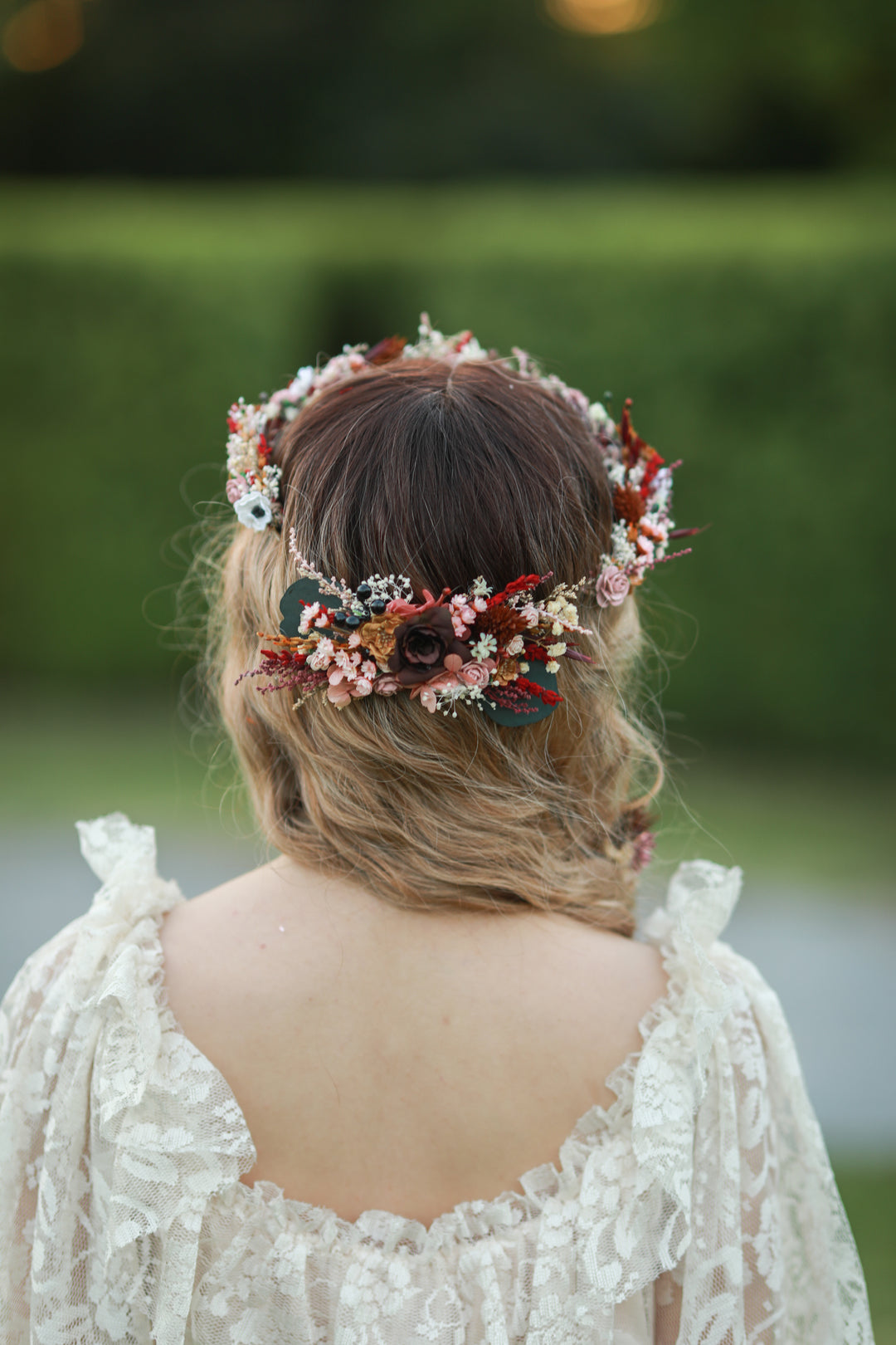 Blush and burgundy bridal hair comb with roses, white anemones, red dried florals and eucalyptus worn in bridal updo, handmade by Magaela