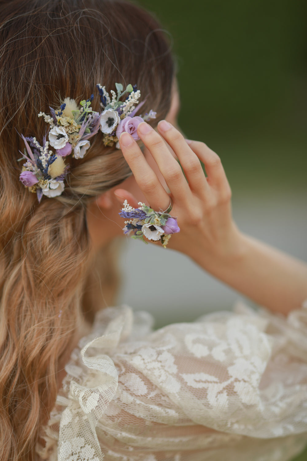 Person wearing a floral hairpins and ring with a blurred natural background