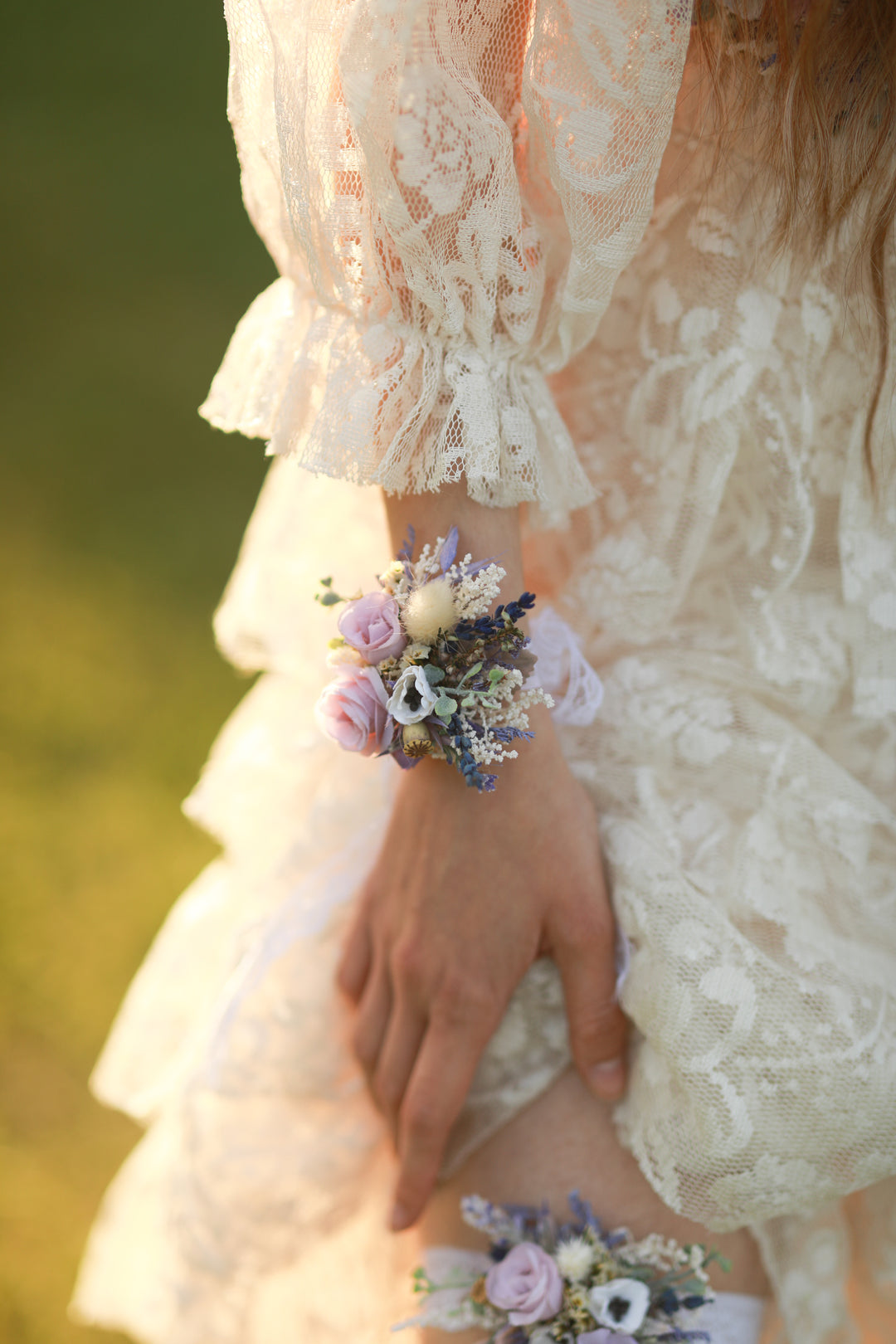 Close-up of a person wearing a lace dress with a wrist corsage against a blurred green background