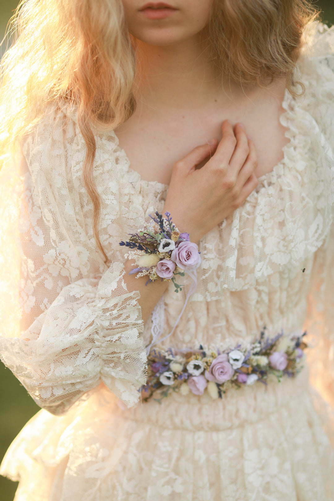 Woman wearing a floral corsage and holding flowers in a softly blurred outdoor setting