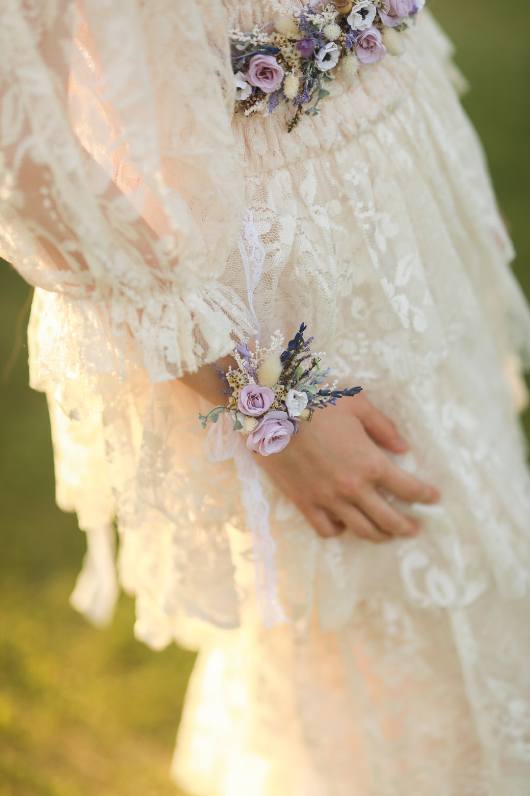 Person wearing a floral wrist corsage and belt, with a blurred natural background