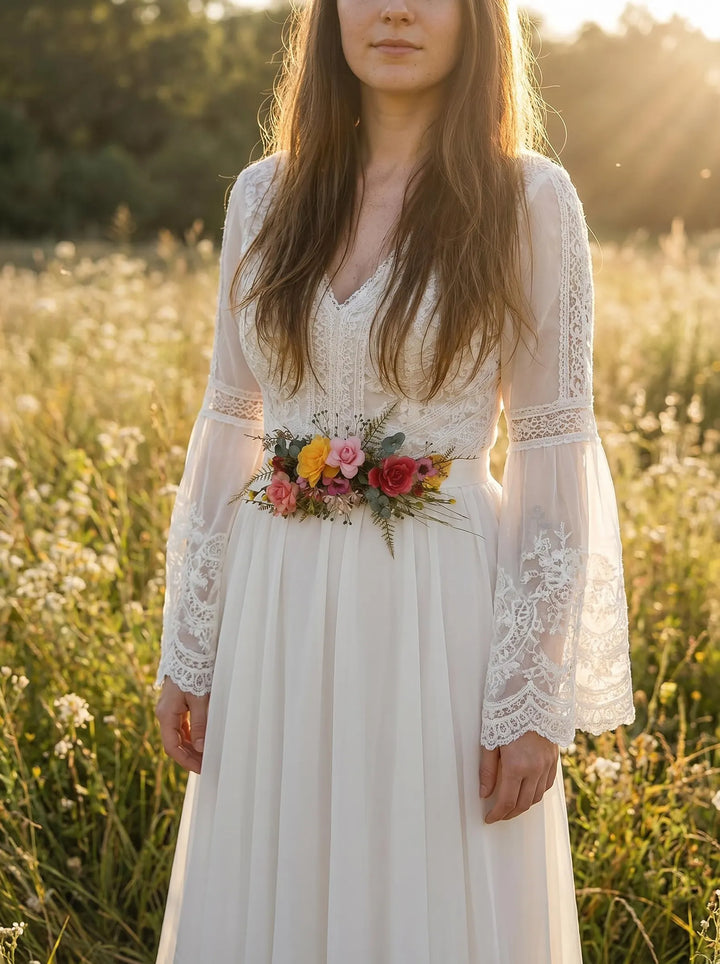 Woman in a white lace dress holding flower red and yellow belt in a field