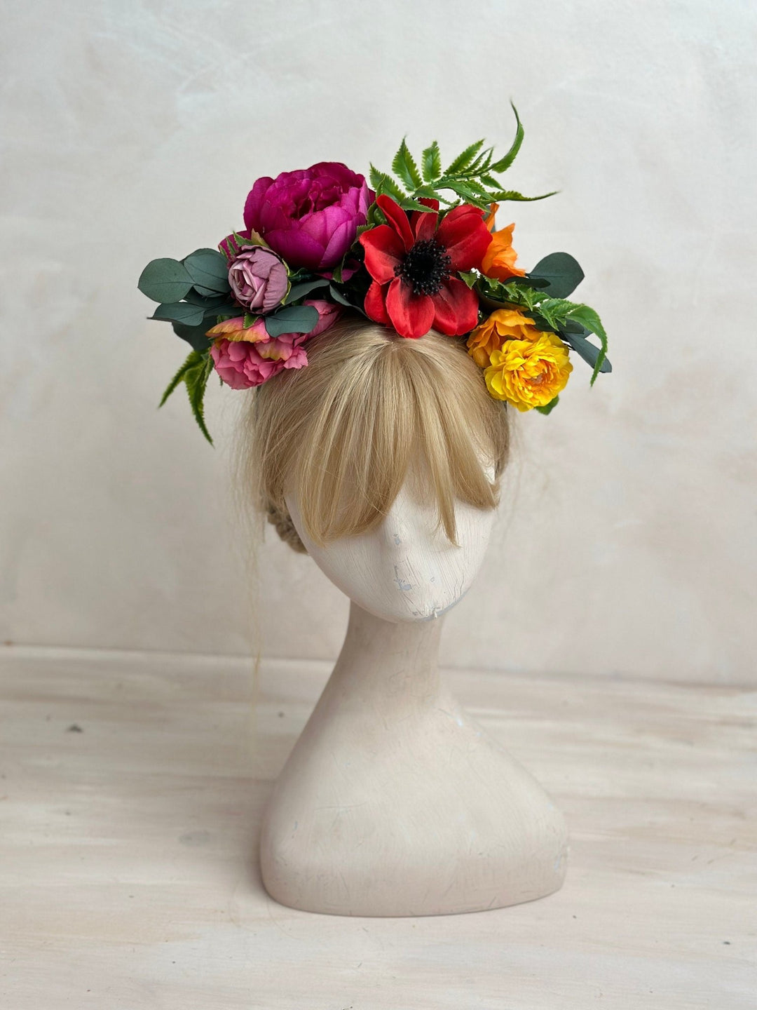 Mannequin head with a colorful floral crown on a white background