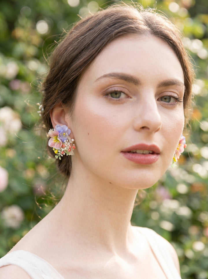 Woman wearing colorful floral earrings with a blurred green background