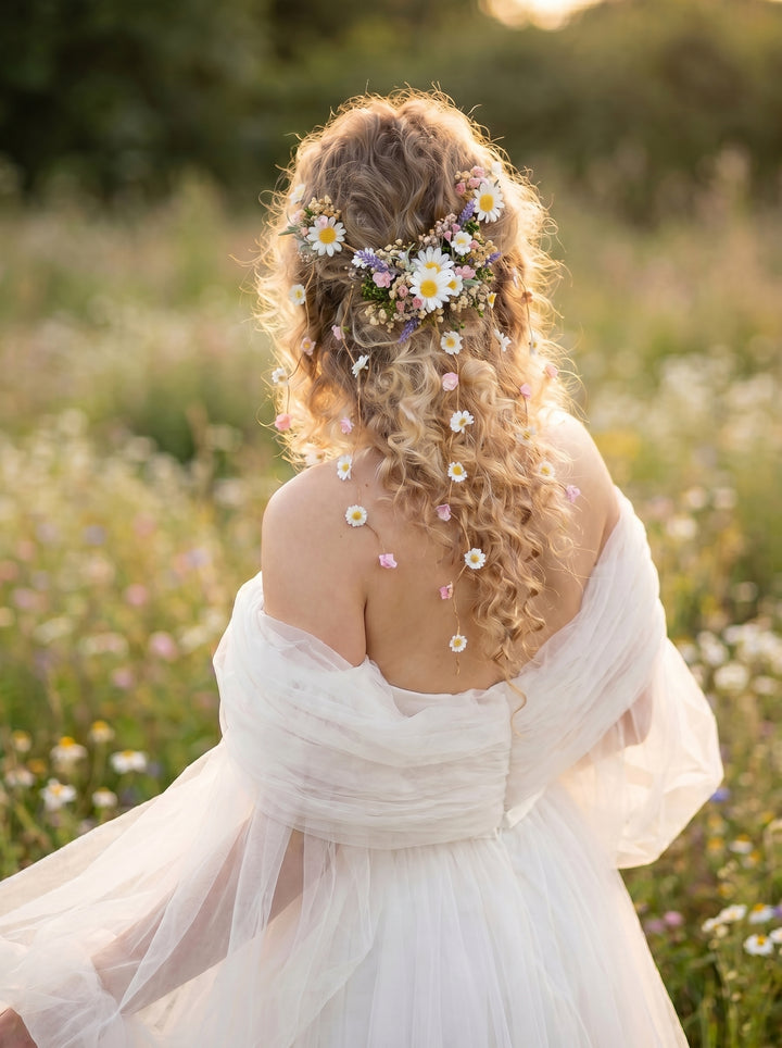 Woman in a white dress with flowers in her hair standing in a field of wildflowers.