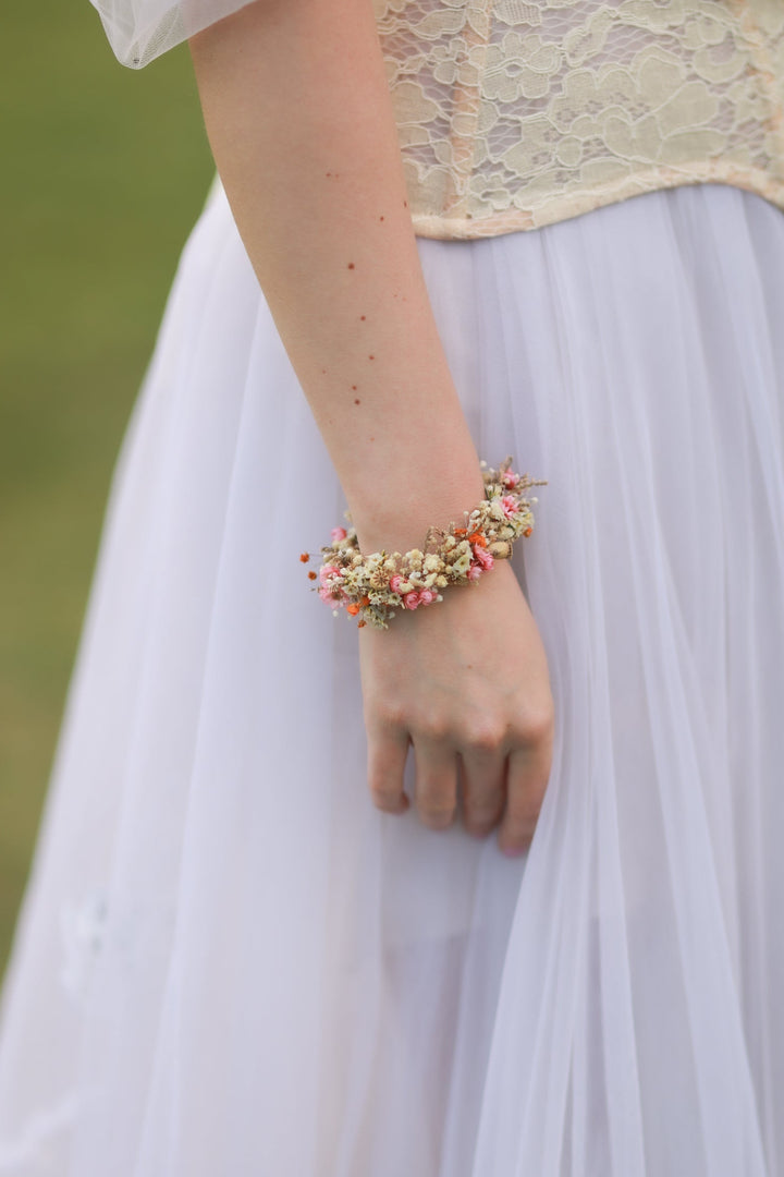 Person wearing a floral bracelet with a blurred natural background