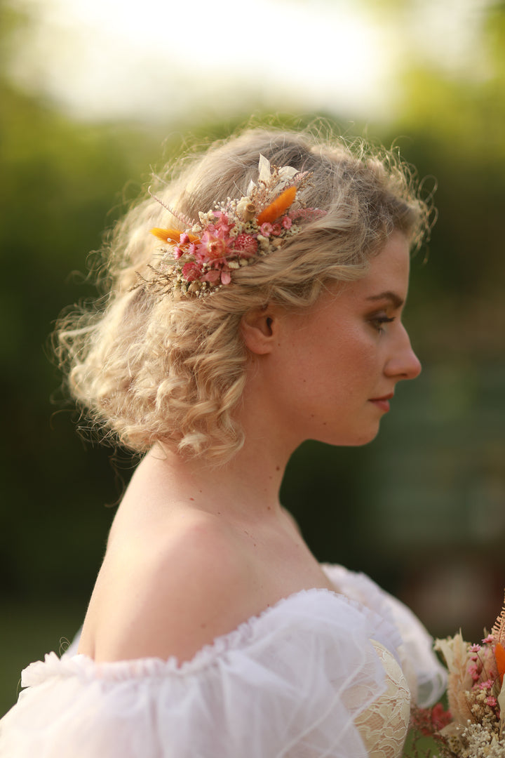Woman with floral hairpiece and white off-shoulder top outdoors