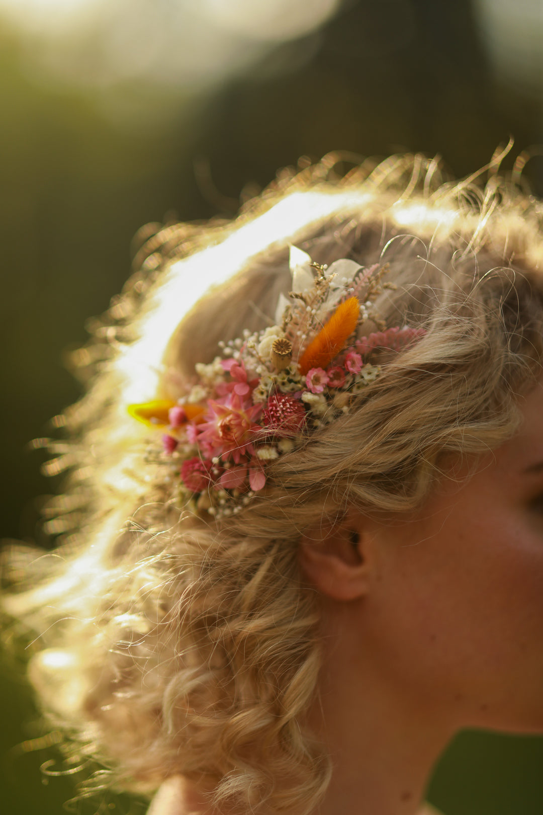 Close-up of a person's head with a decorative rustic dried hair comb featuring flowers and beads.