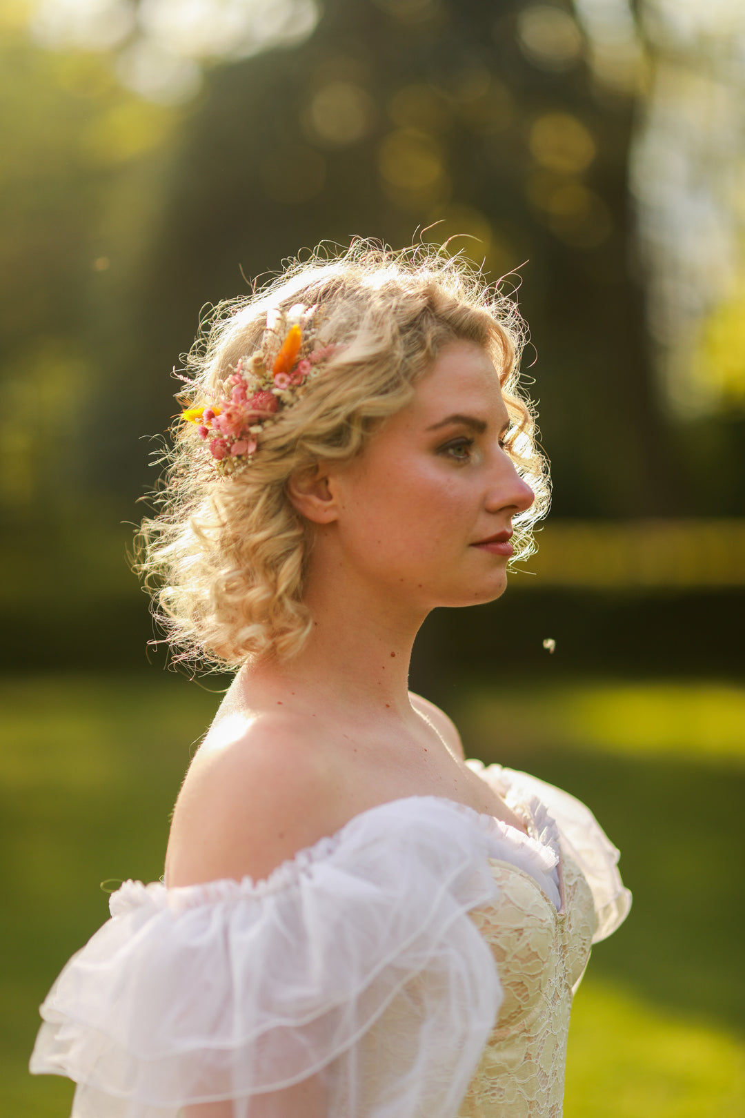 Woman in a white dress with floral hairpiece standing outdoors