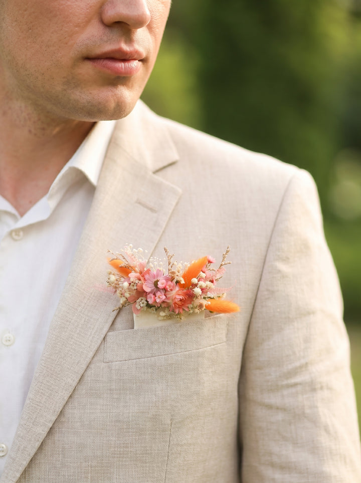 Man wearing a light gray suit with a floral boutonniere outdoors