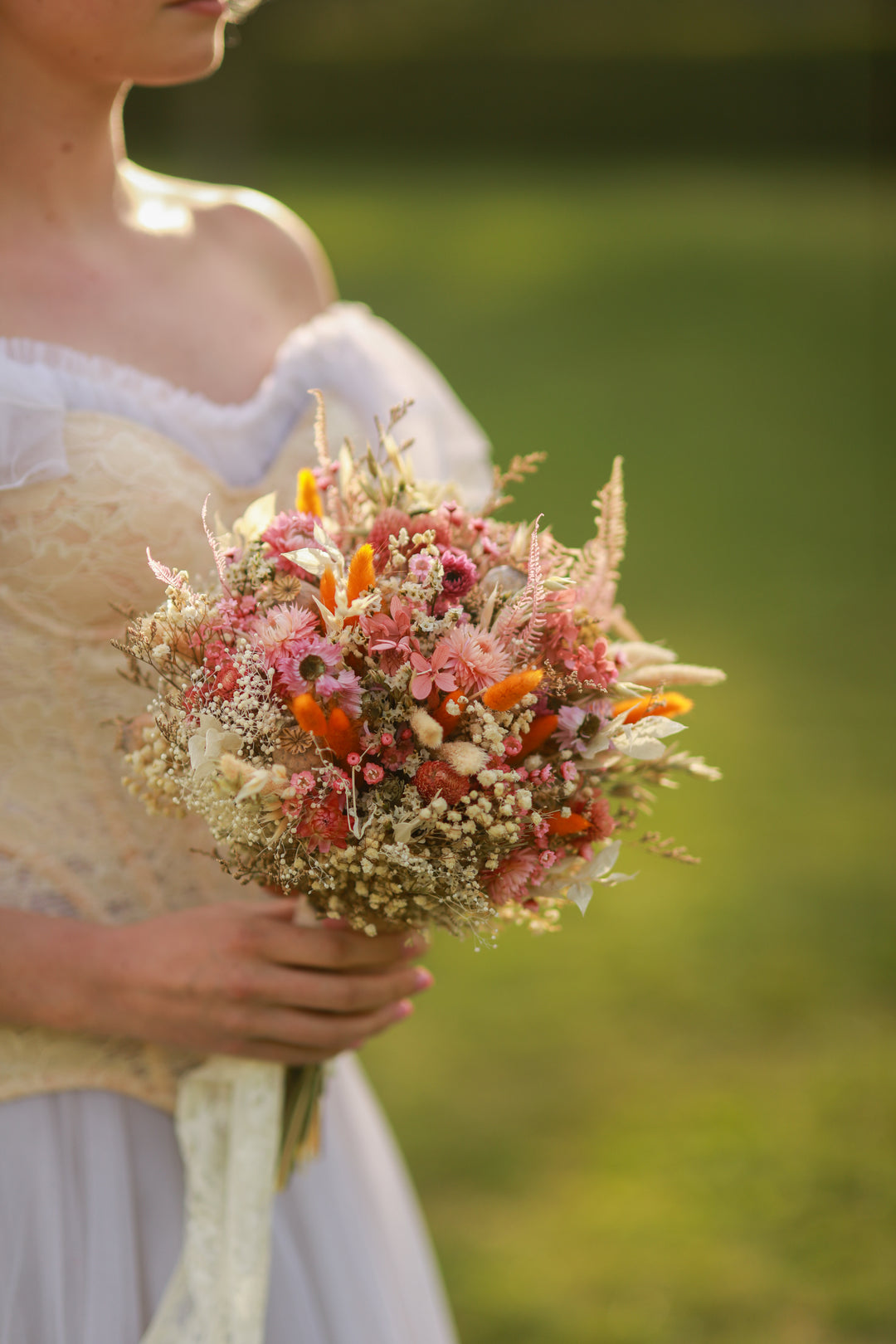 Person holding a bouquet of flowers with a blurred green background