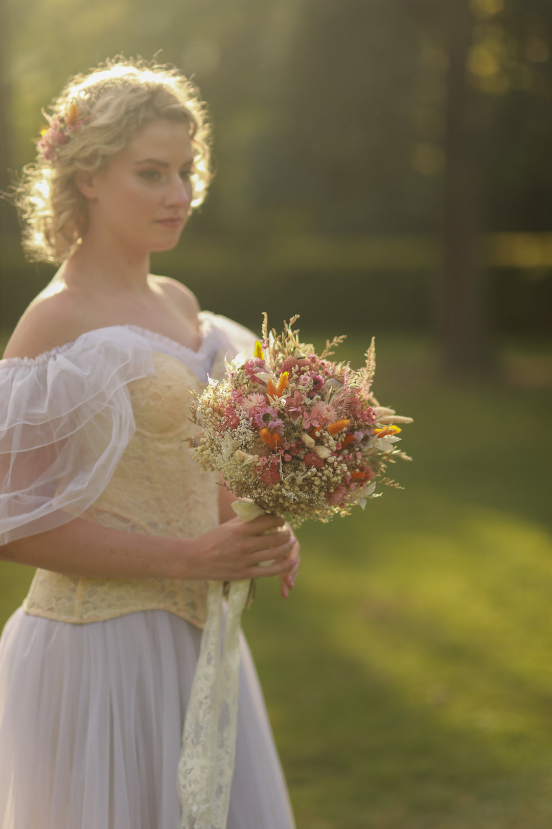 Woman in a white dress holding a bouquet of flowers outdoors