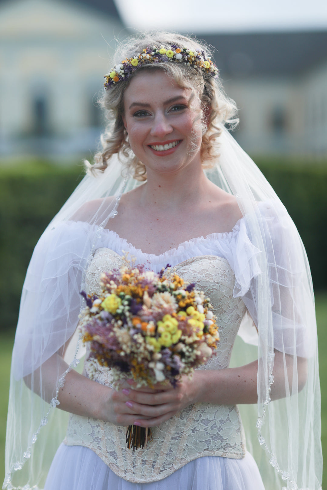 Woman in a wedding dress holding a bouquet of wild flowers  with a blurred background