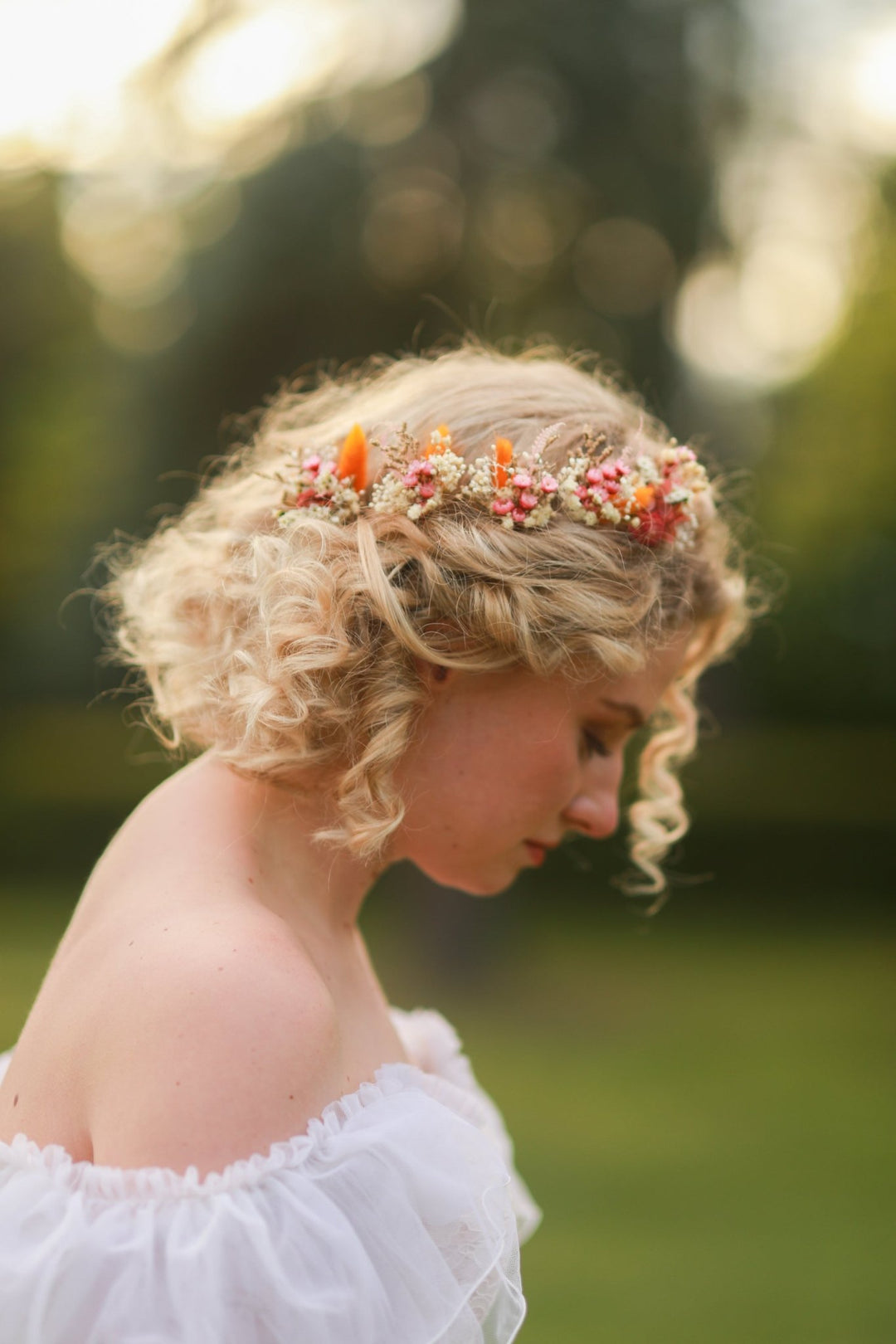 Woman with floral pink, ornage and cream hairpins in a natural setting