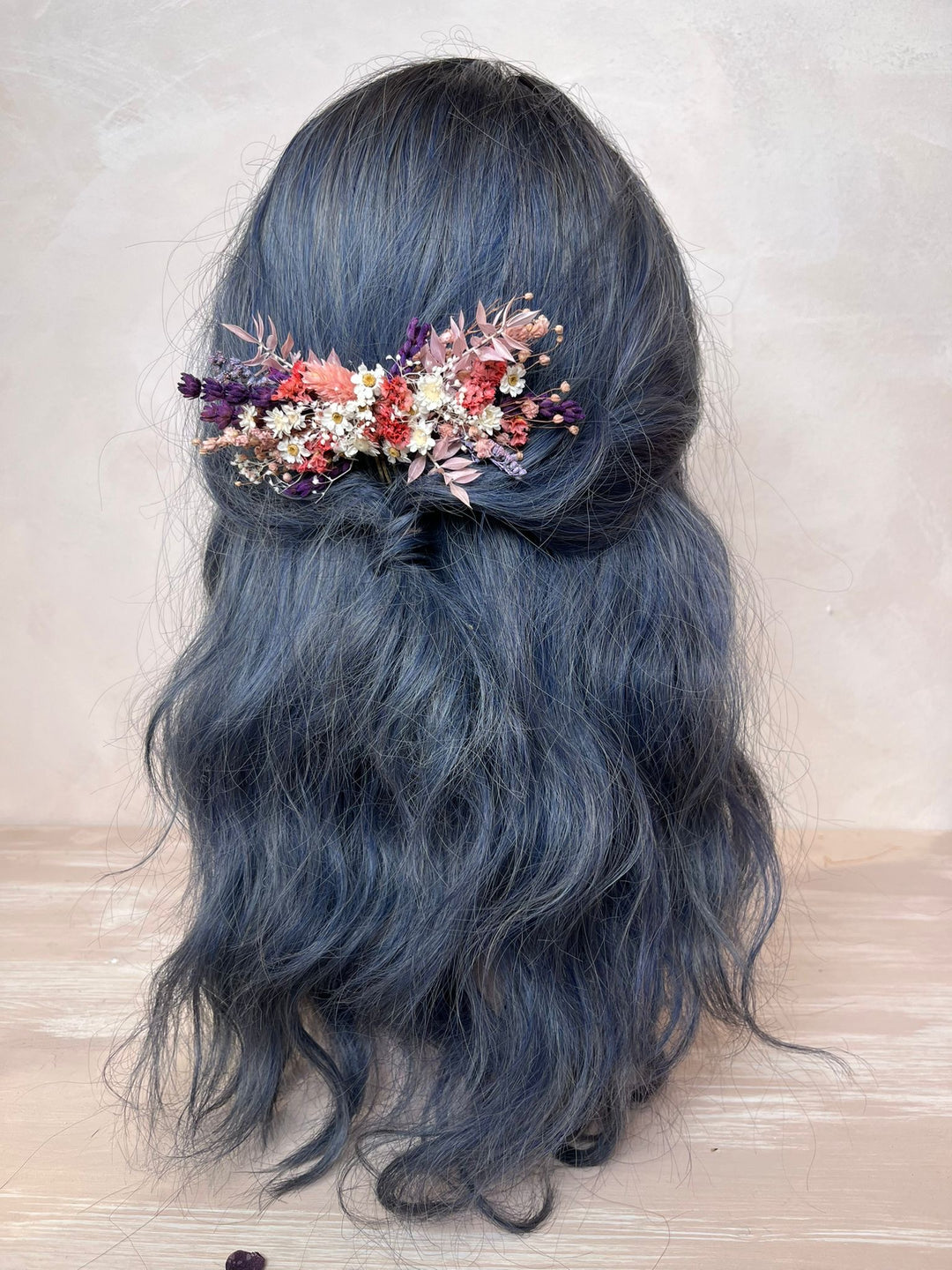 Blue hair with a floral hair accessory on a light background