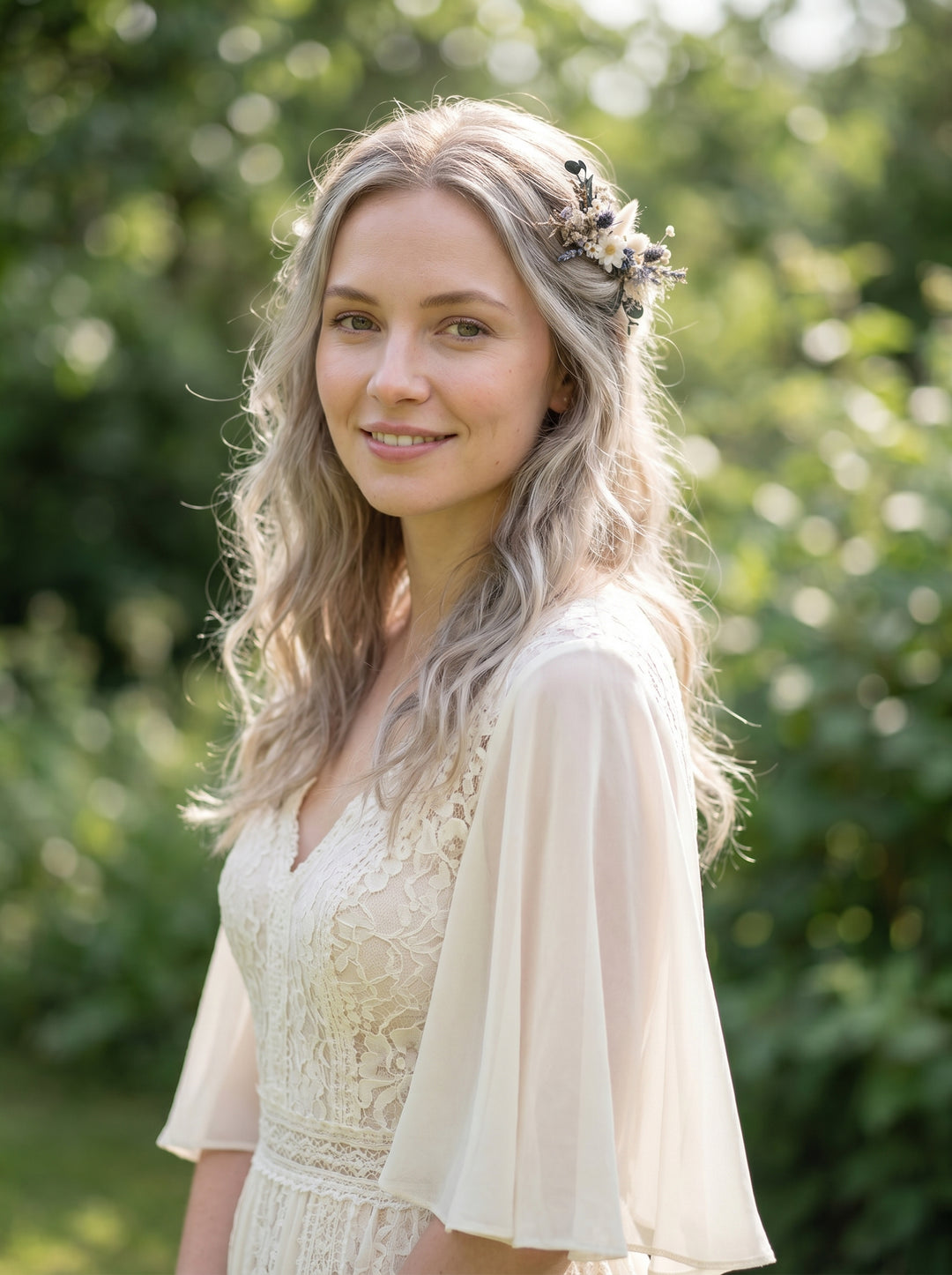 Woman with light-colored hair and a floral headpiece wearing a white dress and beige cardigan outdoors.
