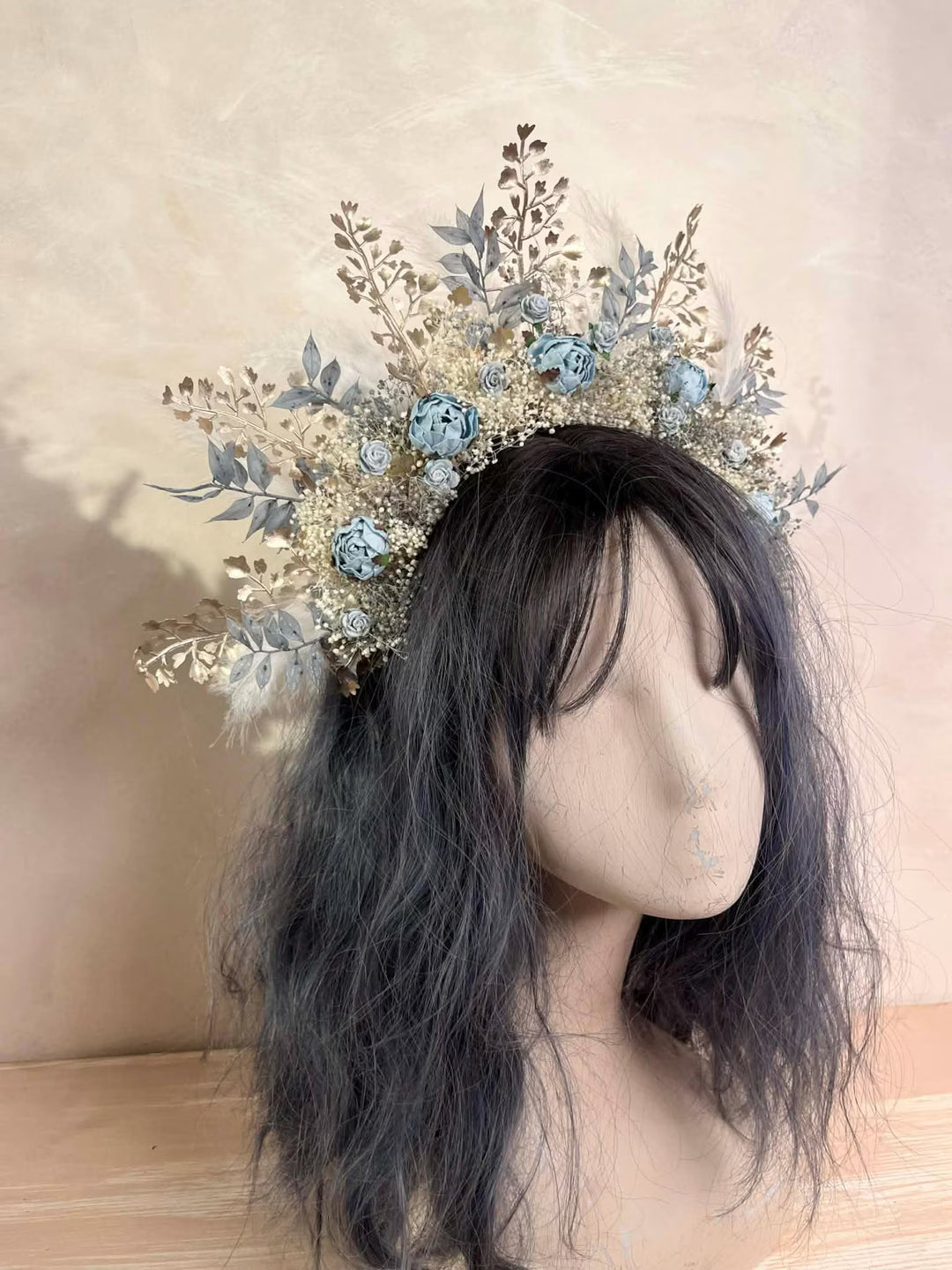 Floral headpiece on a mannequin head with dark hair against a neutral background