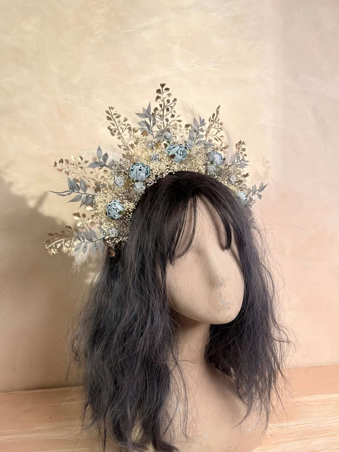 Decorative headpiece with flowers on a mannequin head against a beige background