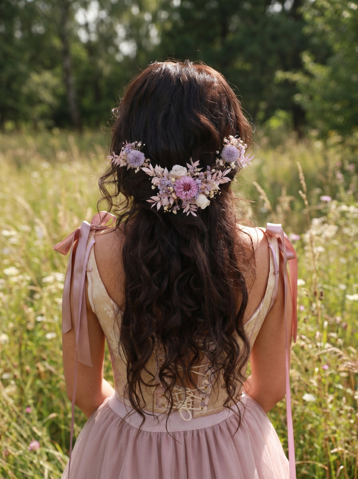 Woman with floral hair accessory in purple tones standing in a field of flowers