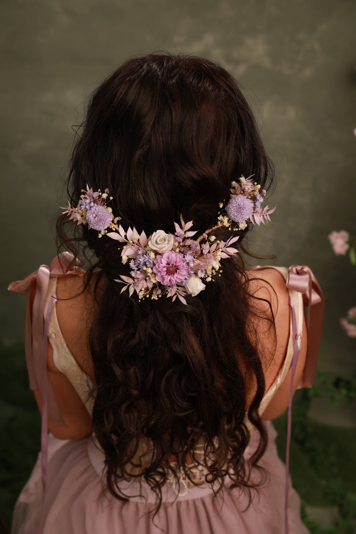 Woman with floral purple preserved hairpiece against a green background